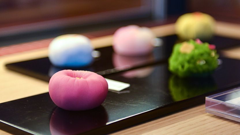 A bowl of matcha tea next to delicate wagashi sweets